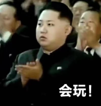图片中显示金正恩在一群人中鼓掌，他穿着黑色衣服，表情看起来有些惊讶。图片下方有文字“会玩!”，通常用于表达对某人做法或想法的赞赏、佩服，认为对方很有创意或很会做事。