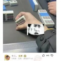 这是一张趣味麻将梗图，画面展示了麻将桌上一只手拿着「四万」麻将牌的场景，同时在画面下方P上了带有「？？」的疑惑表情包。利用「四万」与「死完」的谐音，营造出摸到这张牌时的疑惑、不解的搞笑氛围，调侃打麻将时摸到谐音寓意不吉利的牌的心情。