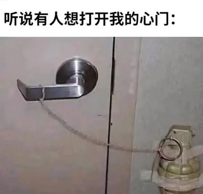 这是一张文字加注的静态梗图，图片上方配有文字“听说有人想打开我的心门：”，下方是经过创作的现实场景照片：一个金属门把手被铁链连接着手榴弹的拉环，将抽象的“心门”具象化为被危险物品锁住的实体门，用夸张、荒诞的方式比喻自己的心门紧闭，暗示任何试图打开自己心门、走进自己内心的行为都会带来“爆炸”般的“危险”，以此表达拒绝他人靠近、不想被打扰的封闭情绪，通过这种反差感制造出搞笑幽默的效果。