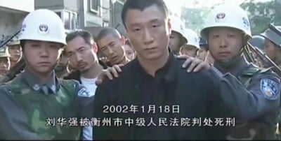 这是国产刑侦电视剧《征服》的经典截图，画面中心是由孙红雷饰演的黑恶势力头目刘华强，他被两名身着迷彩制服、头戴白色执法头盔的人员按住肩膀，处于被控制状态，表情凝重，眼神中带着不甘与沉重。背景里还能看到其他围观或执行任务的人员，画面底部配有白色文字，标注了“2002年1月18日 刘华强被衡州市中级人民法院判处死刑”，还原了剧中刘华强落网后迎来最终审判结局的情节。