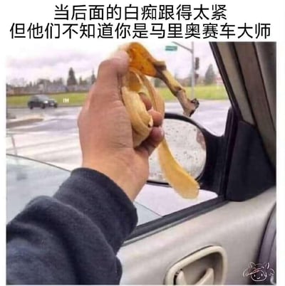 这是一张搞笑梗图，采用车内视角拍摄，一只手从汽车车窗伸出，握着一块吃完的香蕉皮，背景中能看到后方跟车的车辆。图上配文“当后面的白痴跟得太紧 但他们不知道你是马里奥赛车大师”，玩的是任天堂经典游戏《马里奥赛车》里的道具梗——在游戏中香蕉皮是可以丢出的陷阱，能让路过的车辆打滑失控。这张图将现实驾驶场景与游戏玩法结合，把普通的香蕉皮脑补成游戏里的陷阱道具，以此调侃、戏谑那些跟车过近的司机，用幽默的方式表达对跟车行为的无奈与不满，充满了戏谑的搞笑感。