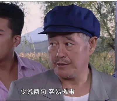 这是一张出自电视剧《乡村爱情》的剧照截图，画面中赵本山饰演的王大拿戴着深蓝色鸭舌帽，穿着灰色外套内搭白色衣物，额头挂着汗珠，侧头看向一旁，脸上露出担忧又无奈的神情，画面下方配有白色字幕“少说两句 容易摊事”。这张图常被制作成表情包，用于在聊天或社交平台中提醒他人谨言慎行，避免因多言惹上麻烦，图中没有双关、谐音梗或暗示内容。