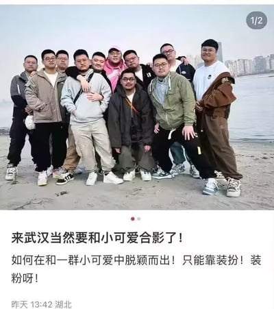 这是一则社交媒体发布的趣味图文内容，上方是一群体型偏胖的男士在武汉江边的合影，背景可见江边的城市建筑；下方配文玩了反讽与双关的文字梗：将这群壮硕男士调侃为“小可爱”，“装粉”一词既指通过装扮让自己脱颖而出，又谐音“装嫩”，用幽默的方式调侃聚会日常，充满趣味。