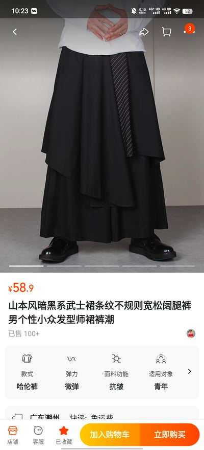 电商平台商品展示截图，主要展示一款黑色山本风暗黑系武士裙条纹不规则宽松阔腿裤。裤子设计独特，采用不对称剪裁，侧边搭配条纹领带装饰，整体风格兼具时尚感与个性。图片上方是商品实物展示，模特仅露出腰部以下穿着效果，搭配黑色皮鞋。下方显示商品价格为¥58.9，已售100+件，并标注了商品款式为哈伦裤、微弹、抗皱、适用青年等属性信息，以及广东潮州发货、免运费等物流信息。界面底部有加入购物车和立即购买按钮，顶部有购物车图标显示3件商品。