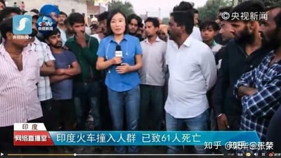 这是央视新闻的直播画面截图，画面中一位央视女记者手持话筒，身处印度当地民众聚集的现场，正在报道一起火车撞入人群的重大安全事故。画面下方的字幕明确标注该事故已造成61人死亡，周围的印度民众围在记者身旁，整体氛围沉重严肃，展现了事故发生后的现场场景。