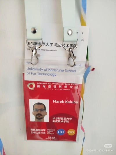 图片展示了一张国际基础科学大会的参会证，整体为红色背景，上方印有大会中英文名称“INTERNATIONAL CONGRESS OF BASIC SCIENCE 国际基础科学大会”及标志。参会者姓名为“Marek Kaluba”，所属单位标注为“卡尔斯鲁厄大学 毛皮技术学院”（英文“University of Karlsruhe School of Fur Technology”）。证上还印有“聚焦基础科学 引领人类未来 ADVANCING BASIC SCIENCE FOR HUMANITY”、“中国·北京 Beijing·China”、数字“131”及无限符号“∞”。证件配有白色挂绳，背景中可见彩色条纹。
该图片的幽默之处在于“毛皮技术学院”并非真实存在的学术机构，与“国际基础科学大会”的严肃主题形成反差，疑似通过P图制作的搞笑或讽刺内容。
