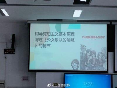 这是一张室内拍摄的投影屏幕照片，屏幕上展示了一个极具反差感的创意课题：用马克思主义基本原理阐述2024年原创TV动画《少女乐队的呐喊》（日文名：ガールズバンドクライ）的情节。屏幕右侧配有该动画的角色群像图和Q版井芹仁菜的形象，画面下方的电子屏显示时间为13:23，左侧的电子时钟显示13:33:00，整体场景看起来像是在课堂或者研讨活动中。严肃的社科理论和青春向二次元动画结合，形成了新奇有趣的反差效果，让人觉得创意十足。