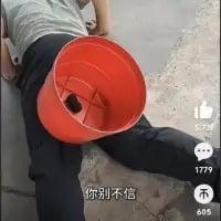 这是一张来自抖音平台的视觉错位类搞笑图片，画面中一名真人坐在地面上，将红色塑料桶放置在自己的腿后方，利用拍摄角度制造出腿被桶“截断”的荒诞视觉错觉。图下方配有文字“你别不信”，进一步强化了这种荒诞感。图片右侧显示了抖音平台的互动数据：5.7万点赞、1779条评论、605次转发，整体画面依靠视觉错位的创意，营造出滑稽、反差的搞笑效果。
视觉错位说明：通过桶的位置和拍摄视角，让观看者误以为桶的位置就是腿部被截断的地方，形成虚假的“断腿”视觉效果。