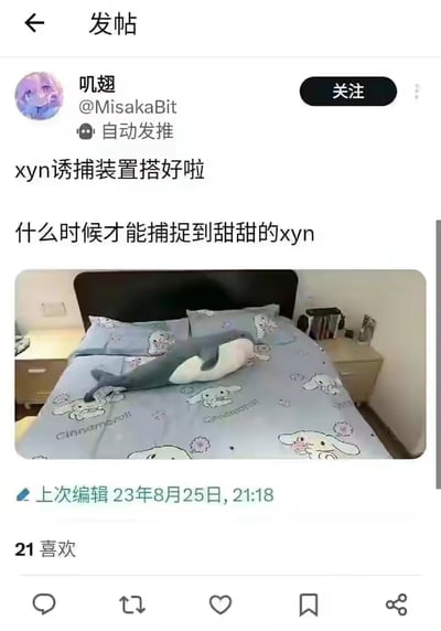 这是一张类推特（X）社交平台的用户发帖截图，用户“叽翅@MisakaBit”发布了自己的床铺照片，床品是印有三丽鸥旗下IP玉桂狗（Cinnamoroll）的浅蓝色套件，床上还放置了一个鲸鱼造型的毛绒玩偶。用户配文以玩梗的语气称“xyn诱捕装置搭好啦”“什么时候才能捕捉到甜甜的xyn”，将温馨可爱的床铺调侃成用于“捕捉”特定对象的装置，表达了对与“xyn”相关的美好期待。帖子显示上次编辑时间为2023年8月25日21:18，目前获得了21个喜欢。