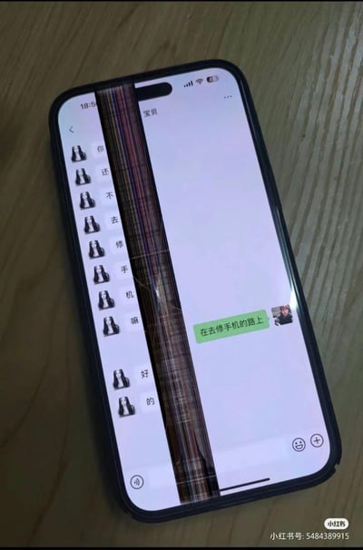 一张手机实拍图，屏幕明显碎裂但仍在显示微信聊天界面。对话内容形成有趣反差：对方催促"你还不去修手机嘛"，而机主回复"在去修手机的路上"，用碎屏手机回复修手机的场景充满黑色幽默。手机放置在木质桌面上，时间显示18:56，信号和电量正常。