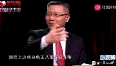 图片为电视节目《这就是中国》的截图，画面中一位穿着黑色西装、佩戴红色领带的男性正激动地伸出右手做出指向动作，表情严肃。屏幕下方配有字幕内容。背景为深色，左上角有“东方卫视”和节目名称标识，右上角有“网易视频”logo，右下角有“观视频”水印。