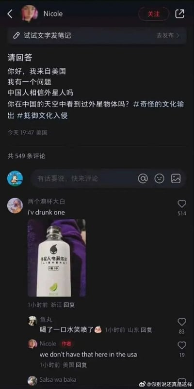 这是一张小红书社交平台的深色模式截图，定位在美国的用户Nicole发布提问帖，询问中国人是否相信外星人、有没有在中国的天空中看到过外星物体，还带上了“奇怪的文化输出”“抵御文化入侵”的话题标签。评论区网友“两个溴杯大白”玩谐音梗，回复称自己喝过外星人，同时附上了“外星人电解质水”的产品照片，后续有其他网友评论表示被该梗逗笑，原发帖者Nicole则回应称美国没有这种东西，整体是利用“外星人”一词多义制造的趣味玩梗内容，笑点十足。