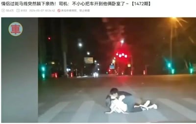 夜晚的十字路口斑马线上，一对情侣躺卧在地亲热，背景是亮着信号灯的路口和远处的车辆。配文调侃道「情侣过斑马线突然躺下亲热！司机：不小心把车开到他俩卧室了~」，司机的话用夸张的比喻，将情侣躺卧的斑马线比作私人卧室，制造出荒诞搞笑的效果，让人觉得又离谱又好笑。