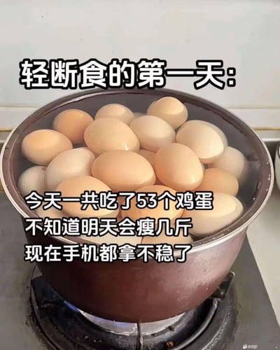 这是一张以“轻断食”减肥热门话题为主题的恶搞梗图。图中一个锅里煮着大量鸡蛋，画面上方有大标题：“轻断食的第一天：”，下方配以夸张的自述：“今天一共吃了53个鸡蛋，不知道明天会瘦几斤，现在手机都拿不稳了。”通过极限夸张来讽刺一些人‘断食’方式不科学，把“轻断食”玩成了“胡吃海塞”，风格轻松搞笑。有“手机都拿不稳”，暗示吃太多导致身体不适。整体以网络自嘲风格表达对减肥热门方式的调侃。

图中隐含双关和夸张，例如“轻断食”本是控制饮食，这里却吃极多鸡蛋，反讽减肥方法的误用。