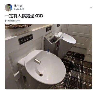 这是一张推特（X）的社交媒体截图，推文作者配文“一定有人搞錯過XDD”，表达对图中厕所设计的调侃。图中近处是一个带有“這是洗手台”标识的白色洗手池，而远处的容器外形与洗手台高度相似，极易被误认成洗手池，但它实际是马桶。这种高度相似的外观设计非常反人类，很容易让人在使用时产生混淆，从而制造出搞笑的效果。