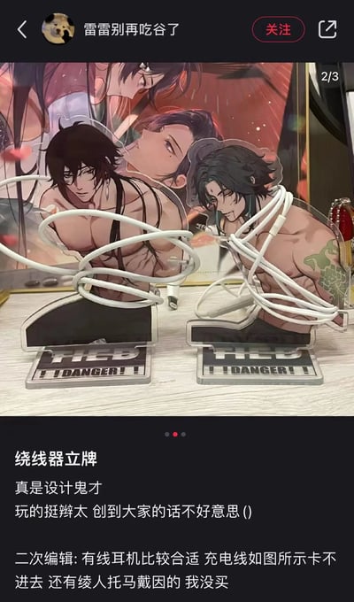 社交媒体用户“雷雷别再吃谷了”分享的帖子，展示了两个二次元男性角色的亚克力立牌被改造成绕线器使用，白色线缆缠绕在角色肌肉线条明显的身体上，底座印有“DANGER!!”字样。配文称其“设计鬼才”，并补充说明有线耳机线适用但充电线卡不进去，还提到未购买绫人、托马、戴因等角色的同款产品。