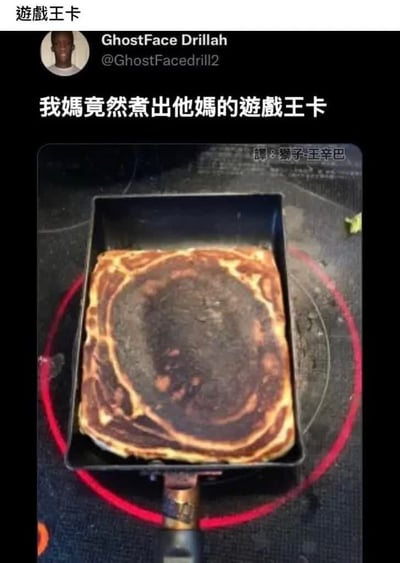 这是一张经过中文翻译的X（原推特）推文截图，图中燃气灶上放着一个方形煎锅，煎锅中的煎饼经煎制后形成了中心深褐色、外围环绕浅黄棕褐色环形纹理，整体外观轮廓和游戏王卡牌十分相似，配文调侃称“我媽竟然煮出他媽的遊戲王卡”，左上角标注有“遊戲王卡”字样，右上角标注了翻译者署名，左上角还展示了原发布者的圆形头像和账号信息。