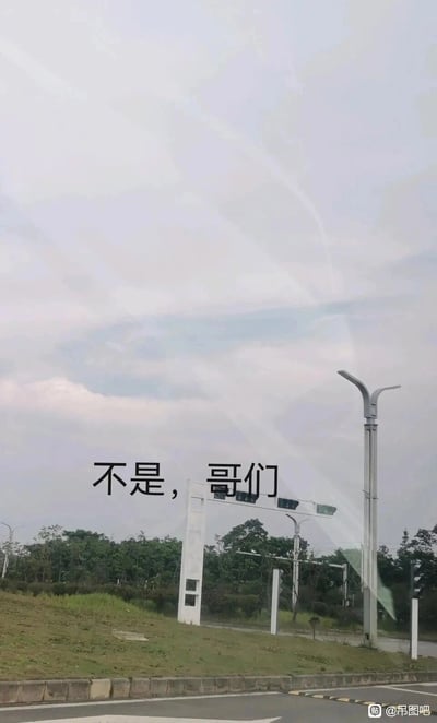 这是一张户外道路场景的实拍静态图，画面上方的天空中，飞机飞行留下的尾迹相互交叉，形成了独特的图案；画面中间添加了口语化的吐槽文字“不是，哥们”，用接地气的表达传递出看到这一奇特天空景象时的惊讶、疑惑情绪；画面右下角带有“吊图吧”的水印，整体风格轻松有趣，是网友分享的日常趣味见闻类内容。
