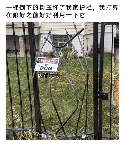 这张图片展示了一个充满生活趣味的创意改造：一棵倒下的树压坏了住户家的黑色铁艺护栏，护栏的金属条被压得变形，刚好形成了一个类似狗的轮廓。住户没有立刻维修，而是巧妙地在这个“狗形”变形护栏上悬挂了一块双语警示牌，英文为“BEWARE OF "DOG"”，中文标注“内有恶犬”，配合上方的文字说明“一棵倒下的树压坏了我家护栏，我打算在修好之前好好利用一下它”，将意外损坏的护栏改造成了一个幽默的防盗警示装置，用诙谐的方式起到警示外人的作用，充满了生活巧思。