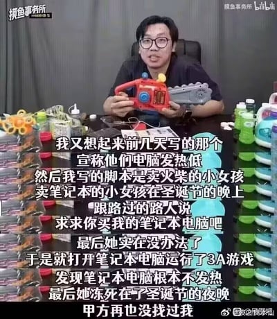 这是B站UP主摸鱼事务所的视频截图，图中戴眼镜的男UP主坐在办公桌后的椅子上，双手拿着一个玩具电锯放在身前，桌面上摆放着各种杂物和玩具。图中覆盖了大段中文字，内容是UP主分享自己给宣传发热低的笔记本写的玩梗脚本：改编《卖火柴的小女孩》，讲卖笔记本的小女孩在圣诞夜卖不出去电脑，走投无路之下打开笔记本运行3A游戏，因为宣传电脑不发热，运行后电脑真的不发热，最后小女孩被冻死在圣诞夜，写完这个段子之后甲方再也没有找过他，内容讽刺了笔记本厂商虚假宣传产品低发热的营销行为。