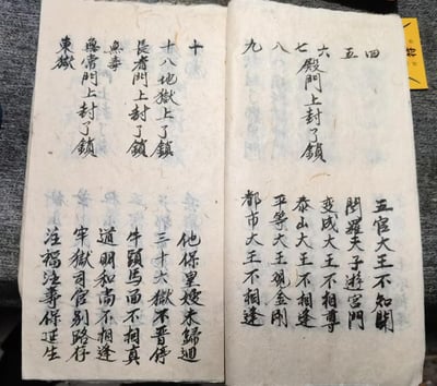 图片展示一本摊开的古老线装书，纸张泛黄且边缘有磨损痕迹，页面以毛笔手写竖排黑色文字为主。左侧页面内容包含“十八地狱上了锁”“长者门上封了锁”“无毒”“无情门上封了锁”“东狱”等字样，下方续有“他保皇嫂未锦还 三十六狱不晋传 牛头马面不相亲 道明和尚不相逢 牢狱司官别路 注福注寿保证生”；右侧页面则有“四 五 六 七 八 九 殿门上封了锁”及“五宫大王不知关 阎罗天子游宫门 变成大王不相尊 泰山大王不相逢 平等大王现金刚 都市大王不相逢”等内容。整体呈现出古朴神秘的氛围，文字内容涉及传统民间信仰中地狱、阎王、各殿门封印等元素。