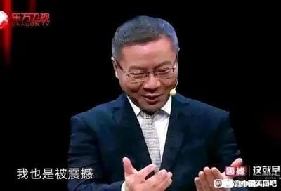 图片为东方卫视节目截图，画面中一名穿着深色西装、佩戴眼镜的中年男子，双手摊开，面露惊讶表情，正在说话。屏幕底部有字幕显示“我也是被震撼”和“这就是”，左上角有“东方卫视”台标，右下角有水印“@全球美拍吧”。整体场景为电视节目中的演讲或访谈环节。