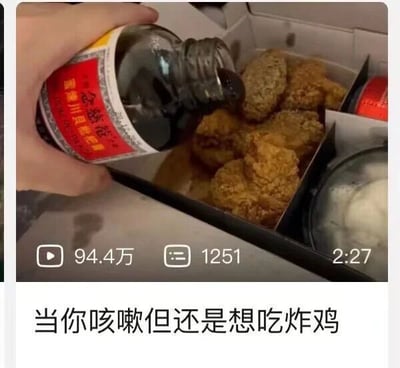 这是一张短视频的截图，画面主体是一只手正将京都念慈庵蜜炼川贝枇杷膏倾倒在一盒外皮金黄酥脆的炸鸡上，视频界面下方显示该视频的播放量为94.4万，弹幕数1251，视频时长2分27秒，截图底部配有文字“当你咳嗽但还是想吃炸鸡”。该内容以幽默夸张的方式，展现了人们在身体不适（咳嗽）却又嘴馋想吃炸鸡时的矛盾心理，通过将治咳嗽的枇杷膏与炸鸡结合的脑洞操作，来调侃这种“嘴馋不顾身体”的日常状态，充满了自嘲式的搞笑氛围，容易引发有类似经历的观众共鸣。