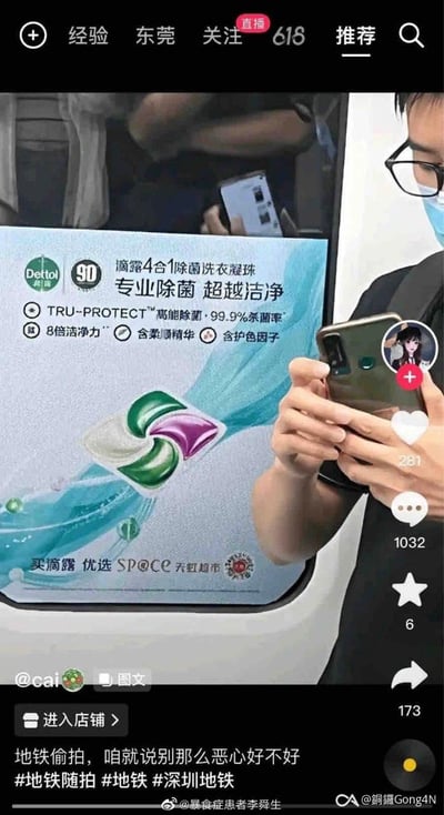 这是一张抖音平台的社交媒体截图，画面主体是深圳地铁车厢内的滴露4合1除菌洗衣凝珠广告，旁边有位戴口罩的男生正双手持手机。发布者配文怒斥「地铁偷拍，咱就说别那么恶心好不好」，并带上相关地铁话题，引发网友对公共场合偷拍行为的反感，图中右侧显示抖音平台的点赞、评论、转发等互动数据。
无谐音梗、双关或暗示内容。
