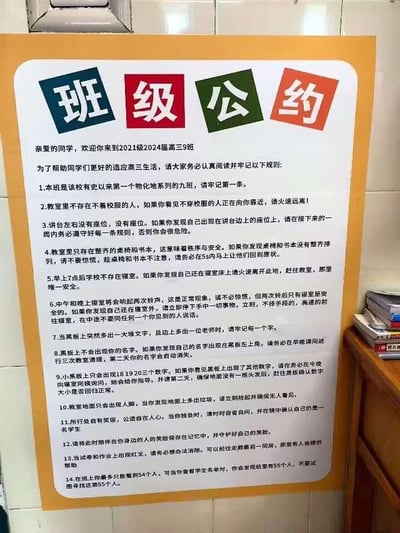 一张贴在墙上的黄色边框海报，顶部有“班级公约”四个彩色大字（蓝底白字“班”、红底白字“级”、绿底白字“公”、橙底白字“约”）。海报内容为2021级2024届高三3班的班级规则，共列出14条充满诡异和超自然色彩的条款，如“教室里不存在不戴校服的人”“讲台右边没有座位”“早上7点后学校不存在寝室”等，营造出强烈的悬疑恐怖氛围，类似“规则类怪谈”风格。