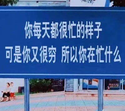 这是一张顶配底文图，画面主体是一块蓝色的标语牌，上面印着扎心的文字：“你每天都很忙的样子 可是你又很穷 所以你在忙什么”。标语牌下方是户外的日常场景，有两位路人平静地坐在路边。这句话直击当代很多人看似忙碌却没有获得相应物质回报的“穷忙”现状，用直白的灵魂拷问引发大众共鸣，没有双关、谐音梗或暗示内容。
针对图中的问题，可能的回答是：这种“穷忙”状态，可能是因为陷入了无效忙碌，被琐事填满时间却没聚焦在能创造收益的事上；也可能是当下正处于积累沉淀阶段，还未到成果变现的时刻；或是收入结构单一，仅靠时间换钱却没有提升自身核心竞争力来增加收入渠道。