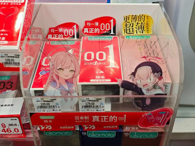 便利店货架上的冈本001系列避孕套产品展示，包装盒上印有不同风格的动漫少女形象。主要展示了红色包装的"真正的001"产品，价格分别为109元和179元。货架上方有促销标签写着"均一薄 001"和"更薄的超薄"等宣传语。