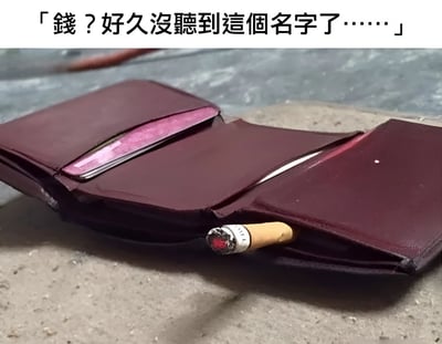 图片展示了一个打开的深红色钱包，平放在灰色水泥地面上，钱包内部空空如也，仅有一根点燃的香烟从夹层中露出，烟头仍有红色火星。图片顶部配有文字“錢？好久沒聽到這個名字了……”，通过拟人化的手法，让钱包“表达”出很久没见过钱的状态，幽默地吐槽了缺钱、钱包空空的窘境，充满自嘲和无奈的搞笑氛围。