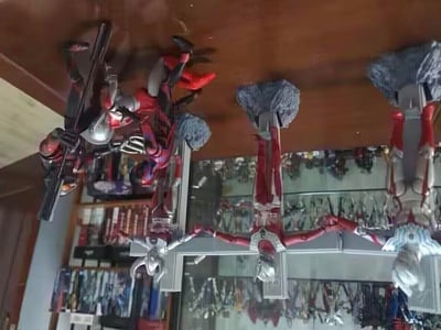 图片展示了一个奥特曼手办收藏架，多个红银色奥特曼模型以不同姿势站立在木质台面上，部分手办配有岩石造型底座。台面下方有玻璃展示柜，内有更多收藏的奥特曼系列模型，整体呈现出爱好者的玩具收藏场景。
