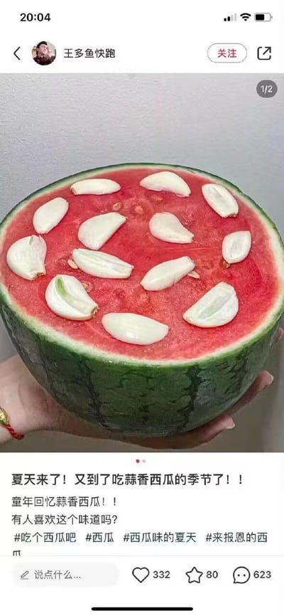 这是一张小红书平台的社交媒体截图，画面主体是一只手捧着半个切去顶部的西瓜，鲜红的瓜瓤上整齐摆放着多瓣剥好的大蒜，形成了极具反差感的“蒜香西瓜”组合。帖子配文充满怀旧感，称“夏天来了！又到了吃蒜香西瓜的季节了！！童年回忆蒜香西瓜！！有人喜欢这个味道吗？”，并附带了#吃个西瓜吧 #西瓜 #西瓜味的夏天 #来报恩的西瓜 等话题标签。截图底部显示该帖子获得了332个点赞、80个收藏和623条评论，这种将大蒜与西瓜搭配的奇特吃法打破了大众对夏日美食的常规认知，既带着童年回忆的怀旧感，又因组合的违和感显得搞笑新奇，引发网友对这种小众吃法的讨论。