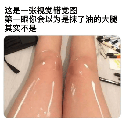 图片上方配有醒目的黑色文字说明：'这是一张视觉错觉图 第一眼你会以为是抹了油的大腿 其实不是'。下方为实拍场景，展示了两根表面光滑反光、形似涂抹过油脂的肢体，膝盖部位的轮廓和光影效果强化了'大腿'的视觉联想。但画面左侧可见黑色口罩边缘，右侧散落着多支彩色马克笔和便签纸，结合肢体比例可推测实际为手臂，通过巧妙的拍摄角度和光影对比制造出'大腿'的视觉误导效果，属于典型的趣味认知错位类图片。