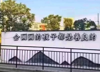 这是一张墙体标语的照片。标语内容是“会画画的孩子都是善良的”，但墙下方被孩子涂鸦成黑色的“山”形，形成了文字与现实的搞笑反讽。画面中，标语试图传递正面的价值观，但涂鸦实际展现了现实情况中孩子并非全然“善良”，而是充满调皮和创造力。这种反差成了网友吐槽、转发的梗点。

谐音/双关：画面本身即是对“会画画”的孩子的直接反讽，形成幽默效果，暗示“会画画”的孩子也会调皮捣蛋。