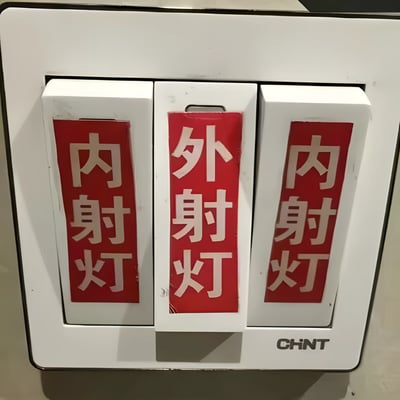 这是一张正泰品牌的三联开关实拍图，左右两个开关贴有红底白字的“内射灯”标签，中间开关贴有“外射灯”标签。
标签使用的“内射”“外射”表述带有不雅的性暗示，和实际控制室内外射灯的功能形成反差，造成了搞笑的效果，容易让人产生联想。