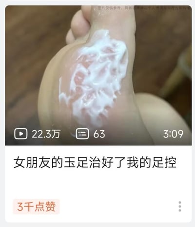 图片展示了一只脚的特写，脚上涂抹着白色的护肤霜。图片上方有部分被遮挡的文字水印，中间显示视频数据：22.3万播放量，63条评论，时长3分09秒。图片下方配有文字“女朋友的玉足治好了我的足控”，以幽默调侃的方式表达内容。