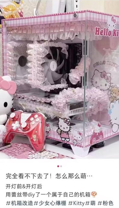 图片展示了一个DIY改造的Hello Kitty主题电脑机箱。机箱主体为粉色与白色格子花纹，四周和内部风扇均装饰有白色蕾丝带，机箱侧面印有多个Hello Kitty卡通图案及“Hello Kitty”字样。机箱旁放置着一个红色的Hello Kitty主题游戏手柄和一个Hello Kitty毛绒玩具。图片下方配有文字：“完全看不下去了！怎么那么萌… 开灯前&开灯后 用蕾丝带diy了一个属于自己的机箱🍄”，并带有#机箱改造 #少女心爆棚 #Kitty #萌 #粉色等标签。整体风格可爱俏皮，将科技产品与少女心元素结合，展现出独特的手工创意。