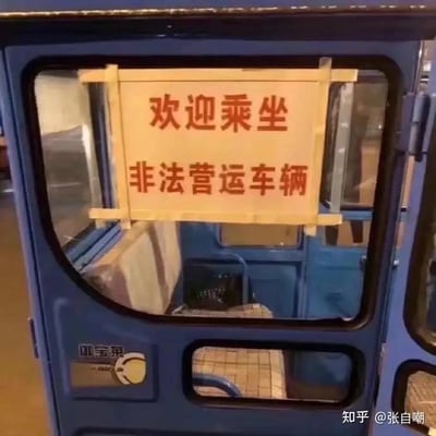 这是一张蓝色御宝莱品牌三轮车的车门实拍图，车门玻璃上用简易木框固定着一块手写标语牌，上面清晰写着「欢迎乘坐 非法营运车辆」。正常来说，非法营运属于违规行为，相关从业者都会刻意隐瞒，而这张图里的标语却反其道而行之，用光明正大的直白表述制造出荒诞离谱的反差感，没有双关、谐音梗等内容，纯粹靠反常识的行为引发笑点。
