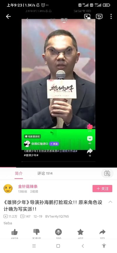 这是一张竖屏的哔哩哔哩平台视频截图，展示了up主“金针菇辣条”发布的关于动画电影《雄狮少年》导演孙海鹏的访谈视频。画面主体是孙海鹏在活动现场手持带有影片标识的麦克风发言的场景，他戴着眼镜，神情专注，双手握住麦克风；下方是B站的视频界面元素，包括up主信息、视频播放数据、互动按钮、相关话题标签以及来源标识。该视频围绕《雄狮少年》的角色设计争议展开，标题称导演表明角色设计为写实派，回应观众争议。