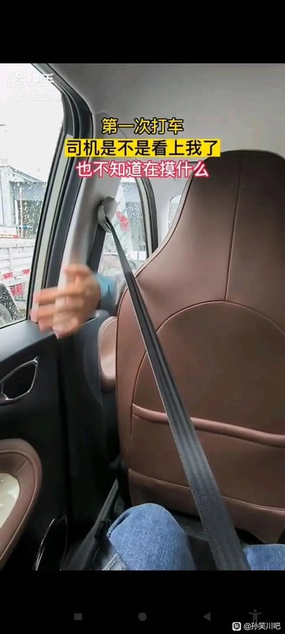 这是一张竖屏手机格式的短视频截图，呈现出租车/网约车的后排乘客视角画面。画面中前排司机的手在座椅旁动作，后排的安全带垂在身前，配文以乘客的调侃语气写道“第一次打车 司机是不是看上我了 也不知道在摸什么”，实际司机是在摸索安全带卡扣，乘客产生了自作多情的误会，通过这种日常小事的反差制造出搞笑效果。