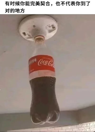 图片展示了一个可口可乐瓶被倒置插入天花板的圆形装置中，瓶口与装置开口完美契合，瓶身自然下垂。图片顶部配有文字：'有时候你能完美契合，也不代表你到了对的地方'。通过可乐瓶与本不属于它的天花板装置意外契合的视觉场景，隐喻了生活中个体即使在某个环境或位置中表现出高度适配，也可能并非处于正确归属的哲理思考。