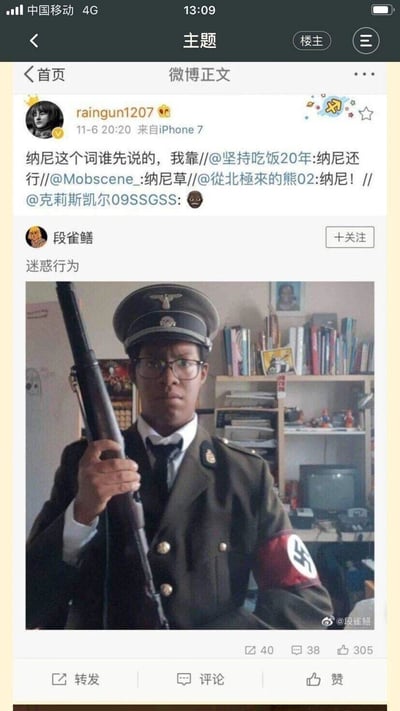 这是一张竖屏的微博平台截图，分为上下两部分：上方是微博用户raingun1207发布的内容，和多位网友通过@转发的形式讨论日语词汇‘纳尼’的起源，传递惊讶情绪；下方是微博用户‘段雀鳝’发布的内容，配文‘迷惑行为’，附带的图片中是一位黑人男性，身着带有特殊标识的军装，手持一把老式长枪，表情严肃，背景是一个摆放着书架、老式电脑的居家房间，整体画面荒诞迷惑，和上方的‘纳尼’（意为‘什么’）形成玩梗呼应，传递出对这一迷惑着装的惊讶感。