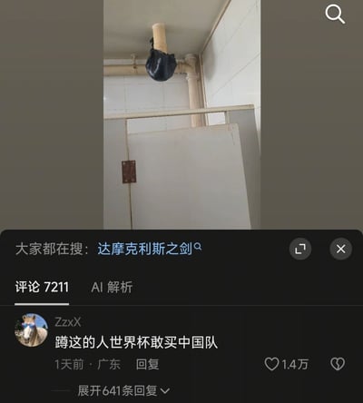 整张图是社交媒体内容截图，上半部分为公共厕所实景，蹲位隔间的天花板下水管道处悬挂着一个黑色塑料袋，正处在蹲位的正上方，存在随时掉落的隐患，该场景被网友关联为“达摩克利斯之剑”；截图下半部分是评论区，显示相关搜索关键词为“达摩克利斯之剑”，高赞评论调侃能蹲在这个位置的人胆子很大，连世界杯买中国队这种事都敢做，该评论获1.4万点赞，整条内容共有7211条评论。