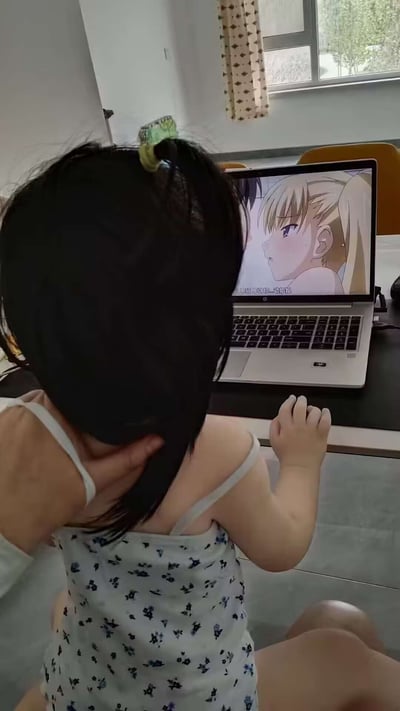 图片中，一名小孩（被大人扶着）正盯着笔记本电脑屏幕，电脑画面上播放的是一部带有一定亲密行为的日漫场景。图片营造出一种“尴尬”、“不合时宜”的幽默氛围，玩梗点在于小孩子不适合观看这种内容却无辜围观，契合“看什么呢”“小孩子别看”等网络梗。此类画面经常用于表达某人不合时宜地看到不适合自己看的东西、或“社死”场面。

本图有一定的暗示氛围和冲突感，属于网络幽默和反差梗。