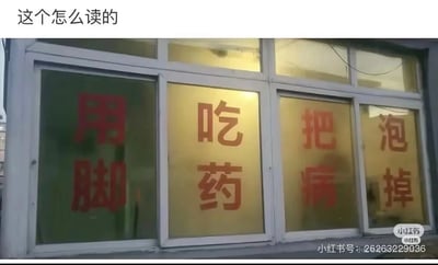 这是一张横版实拍照片，展示了一家店铺窗户上的宣传标语。四个窗户分别竖向印有红色文字：从左到右依次是“用脚”“吃药”“把病”“泡掉”。原本想要表达的是“用泡脚药，把病泡掉”的泡脚治病宣传语，但因为排版将完整语句拆分到不同窗户的竖排文字中，导致容易被误读为“用脚吃药，把病泡掉”，形成了滑稽的歧义效果。图片顶部有白色文字提问“这个怎么读的”，精准点出了标语的歧义问题；右下角带有小红书平台的水印及发布者的小红书号。