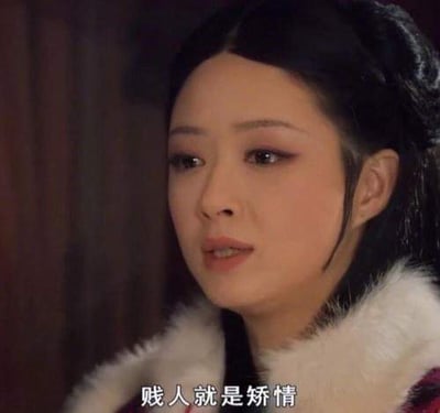 图片为电视剧《甄嬛传》中角色华妃的经典场景截图，华妃身着带有白色毛领的服饰，侧头说出标志性台词'贱人就是矫情'，表情轻蔑不屑。该台词原为剧中讽刺他人装模作样的对白，后成为网络流行语，广泛用于戏谑调侃虚伪做作的行为。