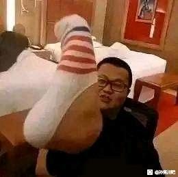 这是一张利用拍摄角度制造视觉错位效果的搞笑图片，画面中一只穿着白、红、灰条纹袜子的脚被置于镜头前方，恰好与后方坐着的戴眼镜男子的头部位置重合，形成了“脚长在男子脸上”的荒诞视觉错觉。男子面向镜头，表情平静，这种巧妙的错位设计制造出强烈的滑稽感，让人忍俊不禁。