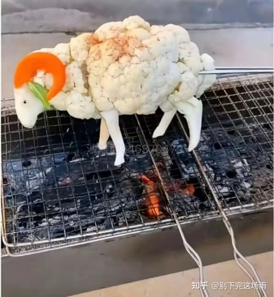 这是一张充满创意的美食实拍图，制作者用菜花作为小羊的身体主体，搭配蛋白、胡萝卜、菜叶、蟹腿等食材，分别制作出小羊的头部、羊角、四肢，将这个逼真的“小羊”造型放置在炭火烧烤架上，模仿烤全羊的场景，趣味十足，让人眼前一亮。
图中没有双关、谐音梗或暗示内容，纯靠食材的创意拼接打造出逼真的模仿效果。